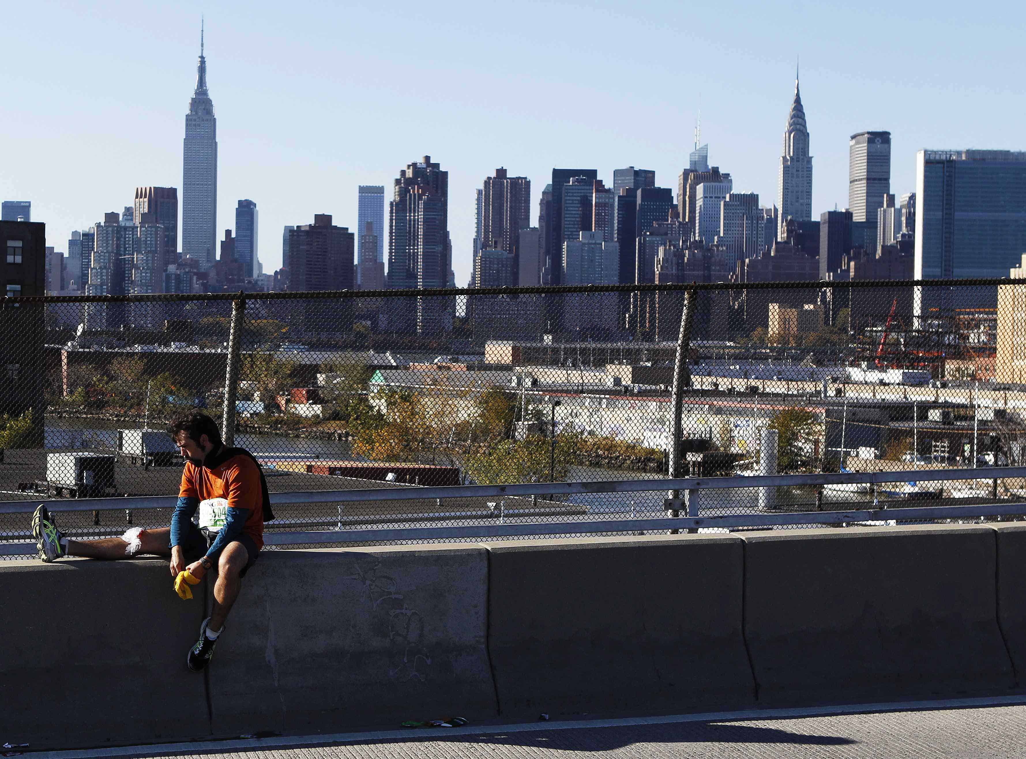 Runner Rancel from Venezuela rests his injured knee on the Pulaski Bridge during the New York City Marathon in New York