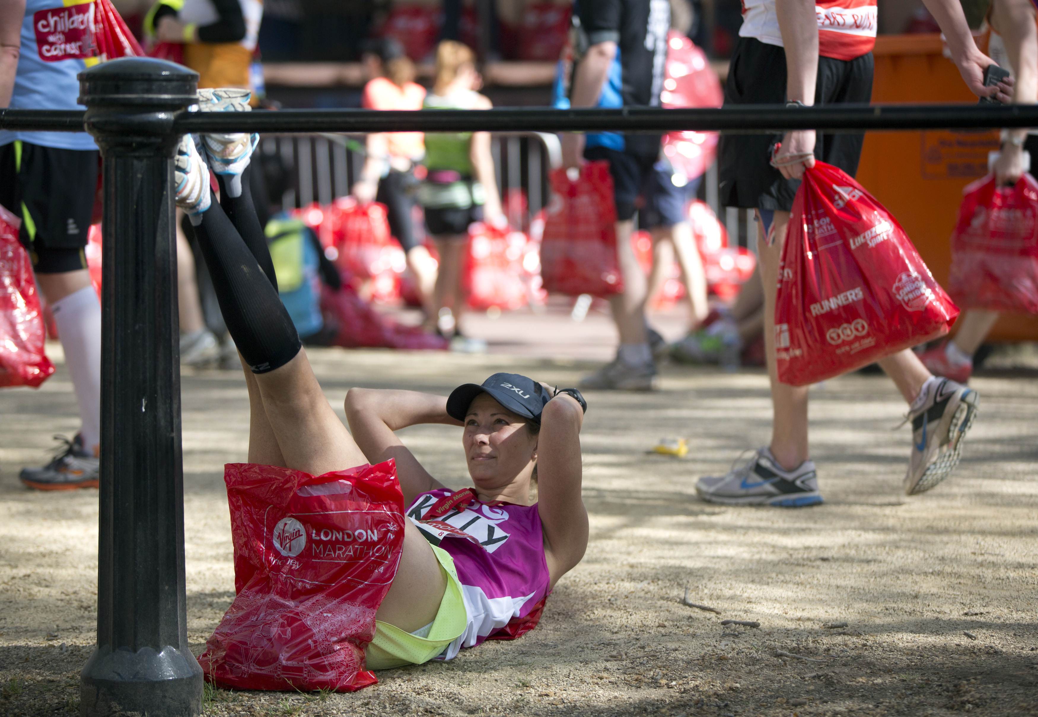 A participant stretches her legs after completing the London Marathon April 13, 2014. REUTERS/Neil Hall (BRITAIN - Tags: SPORT ATHLETICS) Picture Supplied by Action Images